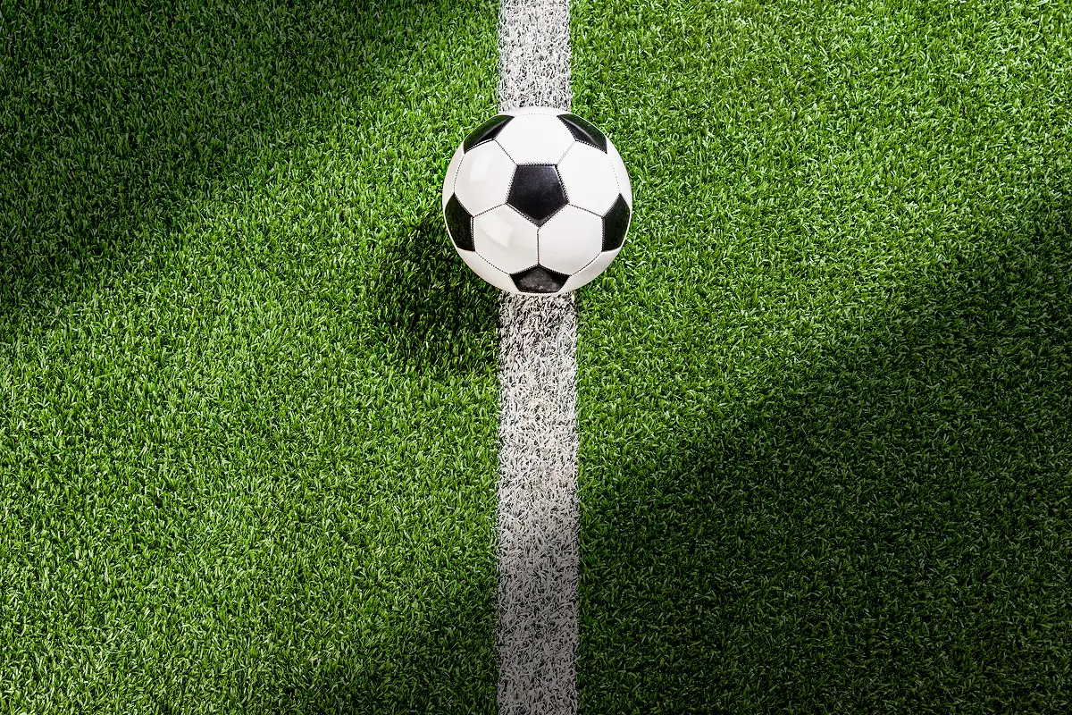 Soccer ball on grass field, white line.