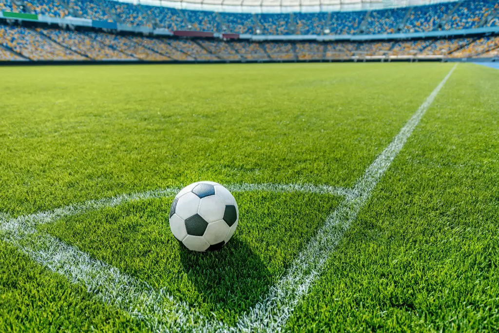 Soccer ball on stadium field corner.