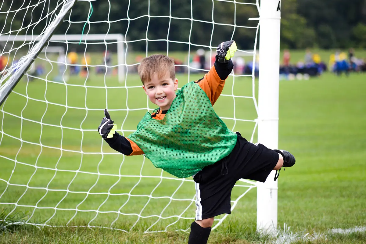 Young soccer goalie celebrating near goalpost.