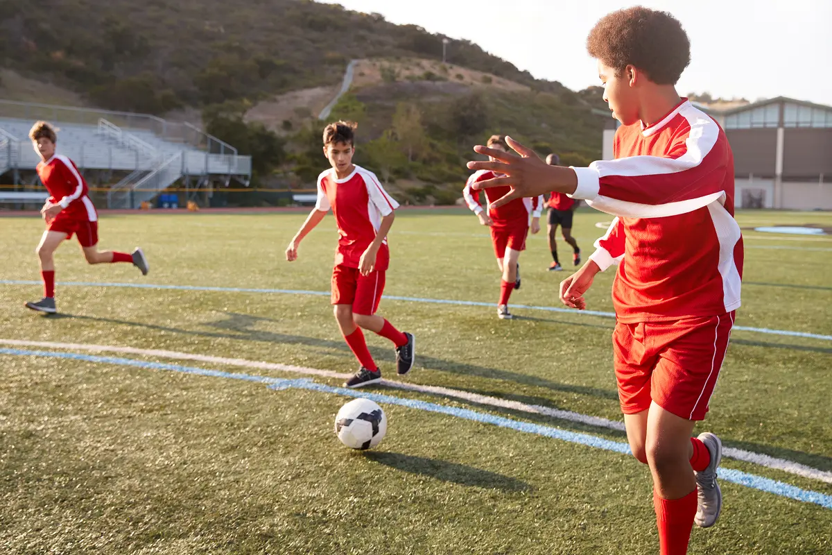 Soccer players in red uniforms on field.